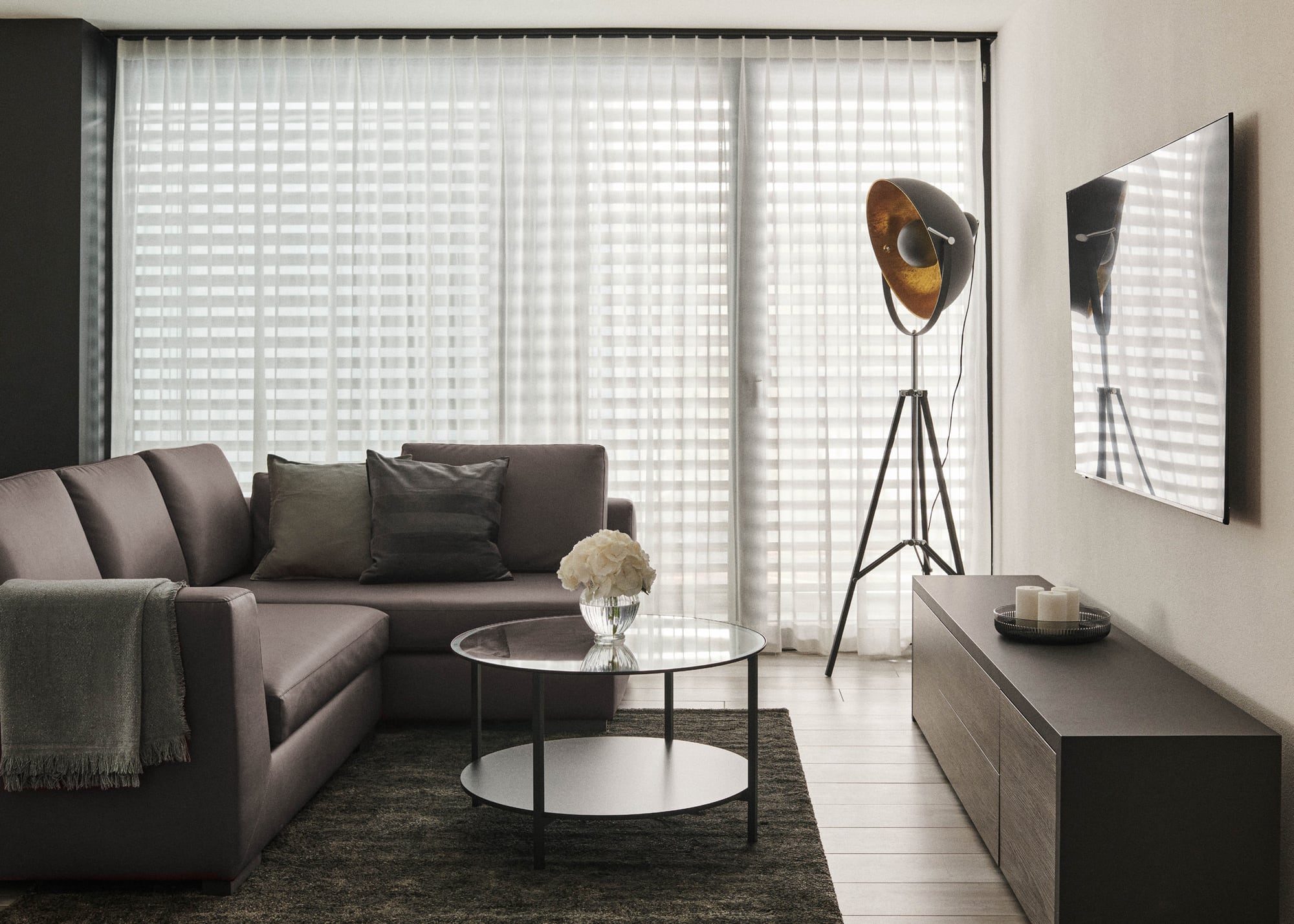 Möbliertes Wohnzimmer eines Three-Point-Apartments mit wandmontiertem Smart-TV